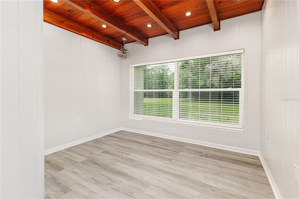 An empty room features wood-plank ceilings, white paneled walls, and light-colored wood-look flooring — 5256 KNIGHTS STATION ROAD, LAKELAND, FL