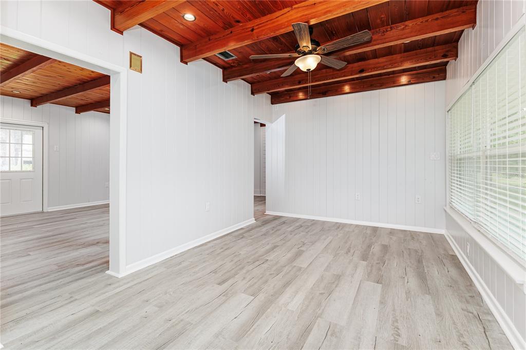 A room with white paneled walls, wood-beamed ceilings, and light-colored wood-look flooring — 5256 KNIGHTS STATION ROAD, LAKELAND, FL
