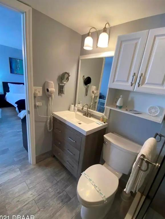 A bathroom features a gray vanity, a white toilet, and a wall-mounted hair dryer — 701 S ATLANTIC AVENUE UNIT 520, DAYTONA BEACH, FL