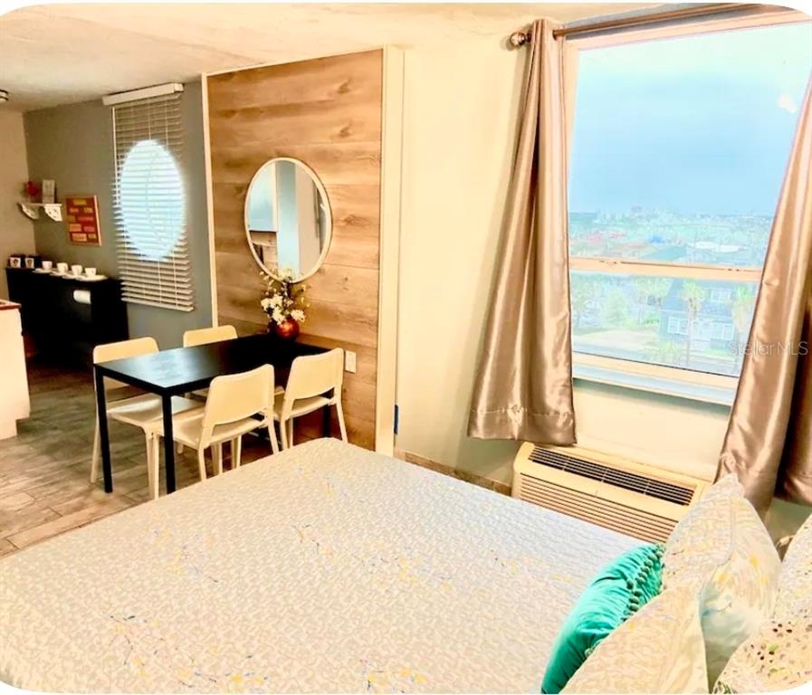 A bedroom with a dining table, a circular mirror, and a window overlooking a city — 701 S ATLANTIC AVENUE UNIT 520, DAYTONA BEACH, FL
