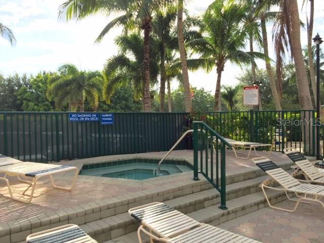 A hot tub sits on a paved deck surrounded by lounge chairs and palm trees — 2060 MATECUMBE KEY ROAD UNIT 2104, PUNTA GORDA, FL
