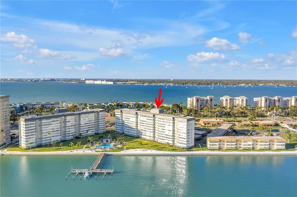 An aerial view shows a multi-story residential building complex situated along a waterfront — 5108 BRITTANY DRIVE S UNIT 405, ST PETERSBURG, FL