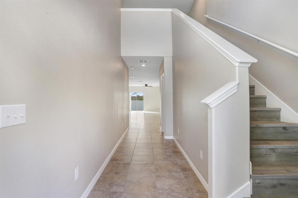 A tiled hallway leads to an open living area with a staircase on the right — 10256 CARLOWAY HILLS DRIVE, WIMAUMA, FL