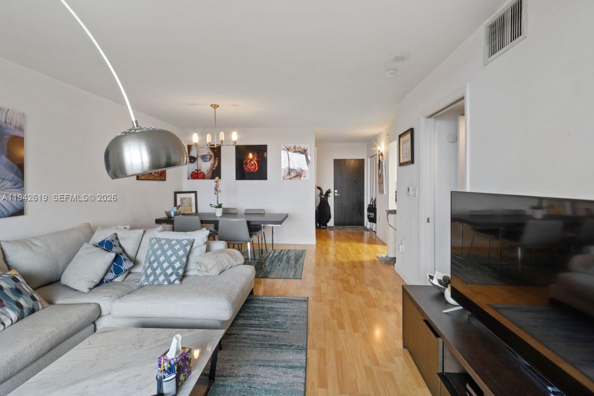 A living and dining area features light wood floors, a sectional sofa, and a balcony — 90 Alton Rd # 807, Miami Beach FL 33139, MIAMI BEACH, FL