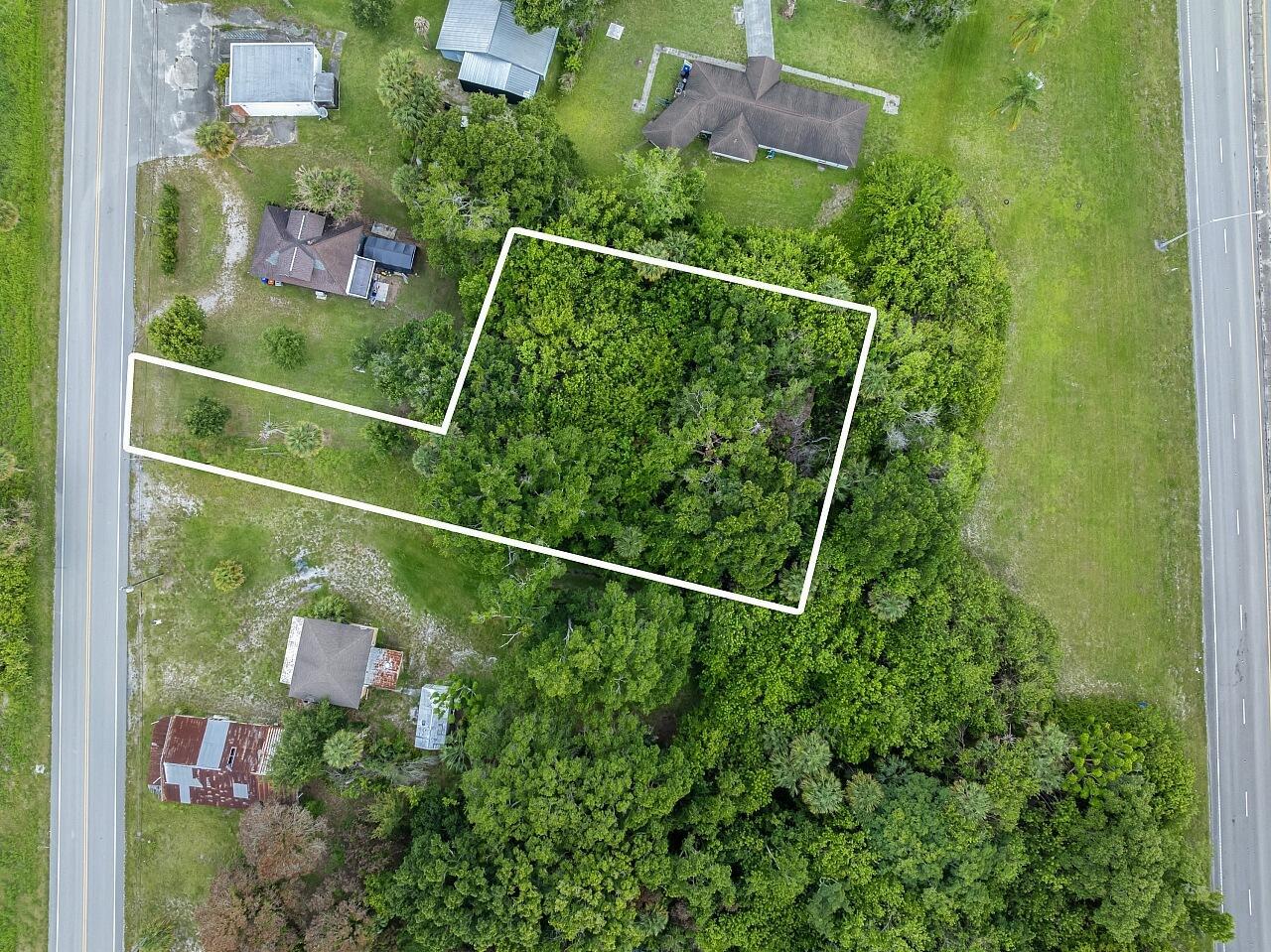 An aerial view shows a wooded, rectangular lot with a narrow access strip to the road — VERO BEACH, FL