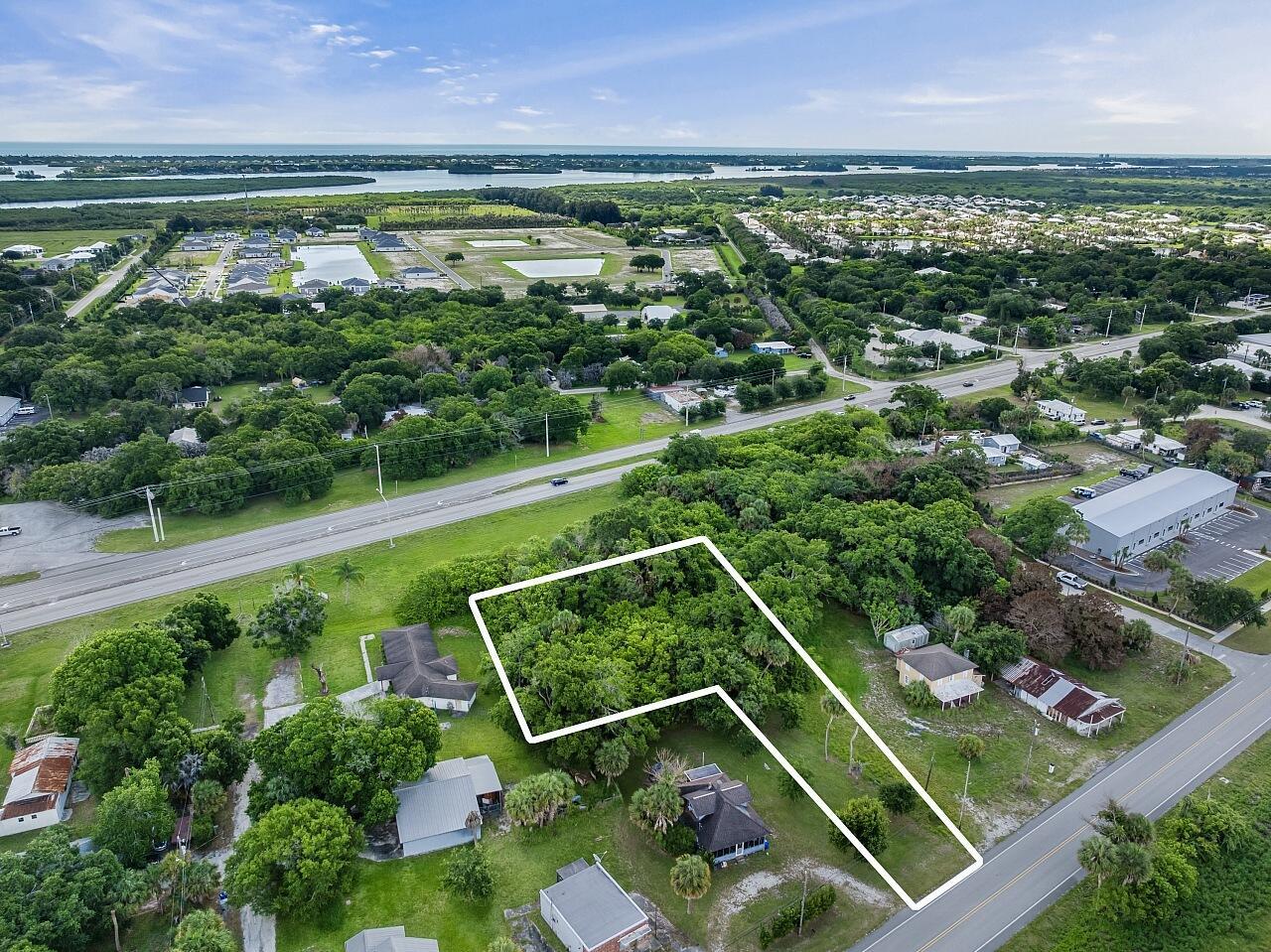 An aerial view shows a wooded, L-shaped lot outlined in white near a road — VERO BEACH, FL