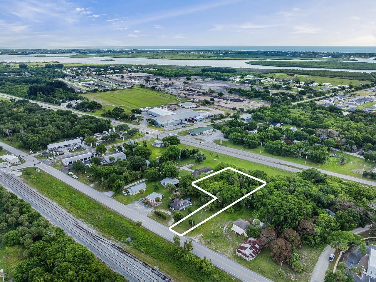 An aerial view shows a wooded, irregularly shaped lot outlined in white near a road — VERO BEACH, FL