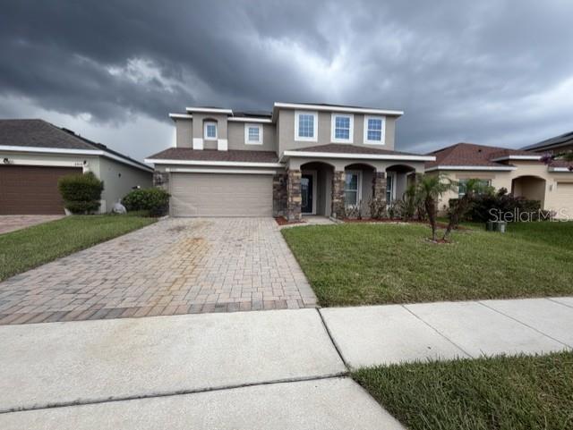 A two-story suburban house features a stone-accented entryway, a paved driveway, and a grassy lawn — 4907 ROCKVALE DR., KISSIMMEE, FL