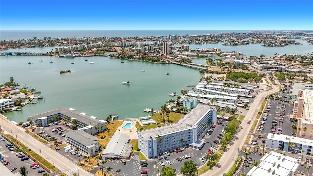 An aerial view shows a coastal area with apartment buildings, parking lots, and a bay — 1868 SHORE DRIVE S UNIT 503, SOUTH PASADENA, FL