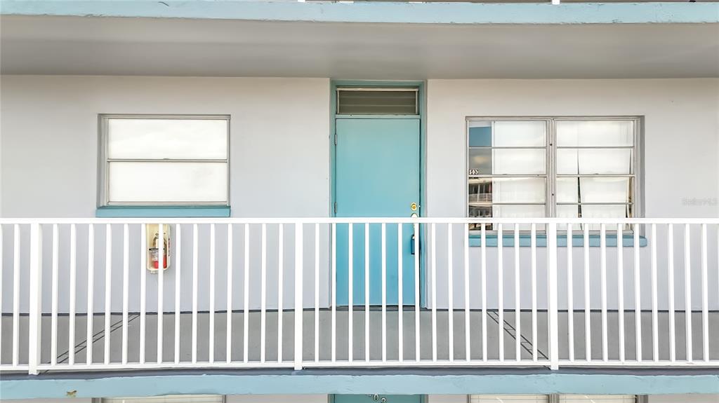 A light blue door with a transom window is centered between two windows on a balcony — 1868 SHORE DRIVE S UNIT 503, SOUTH PASADENA, FL