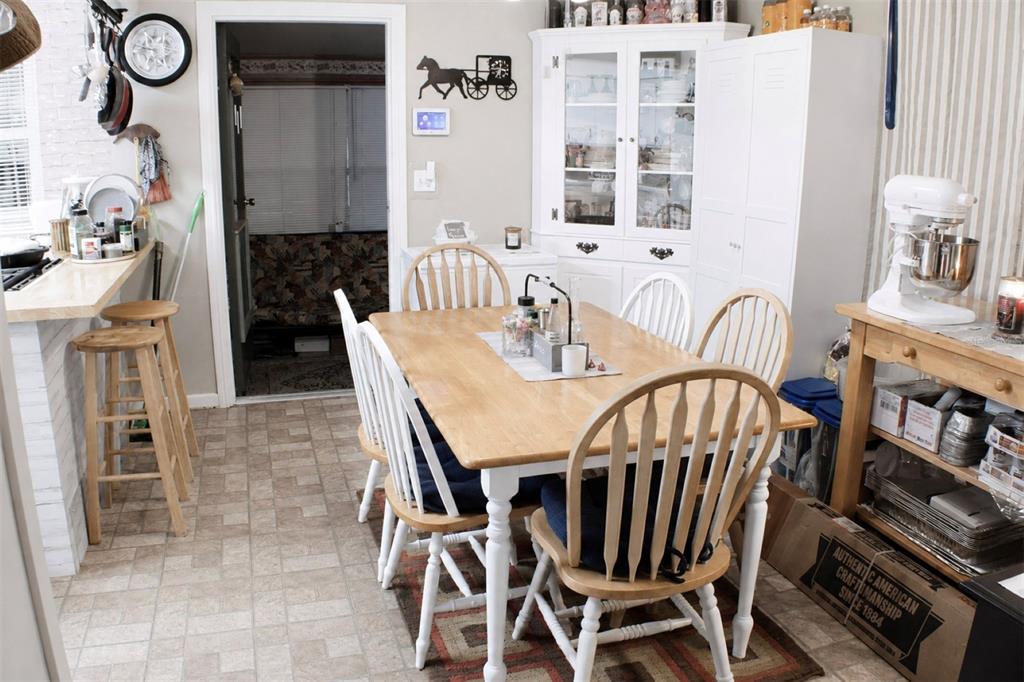 A dining area features a wooden table with white spindle chairs and a white hutch — 1405 28TH STREET NW, WINTER HAVEN, FL