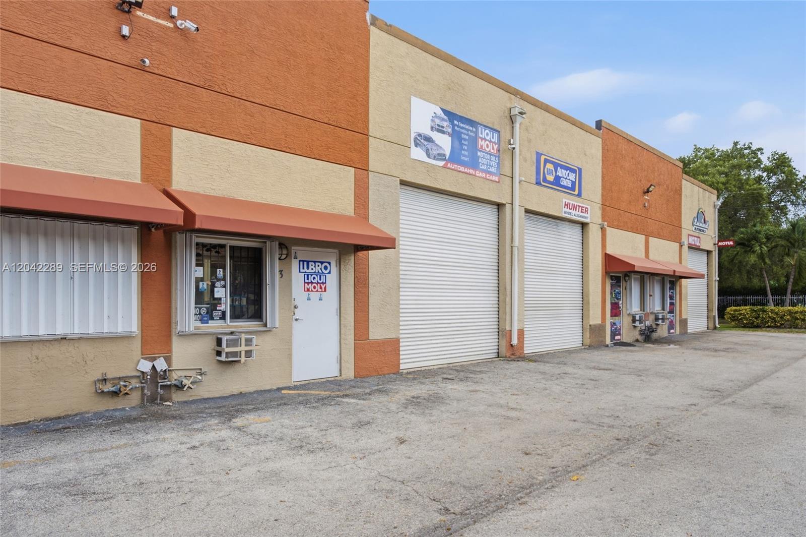 The exterior view shows a commercial building with multiple garage doors and a small office entrance — 11950 SW 144th Ct, Miami FL 33186, MIAMI, FL