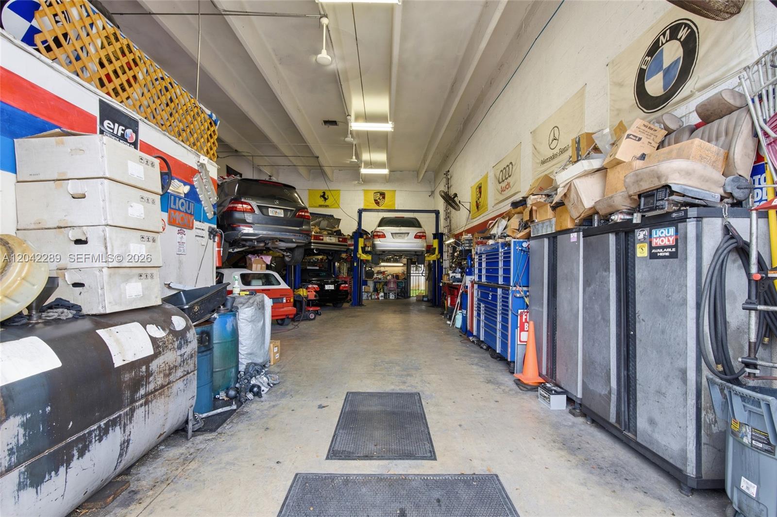 An auto repair shop interior features multiple vehicle lifts, tool cabinets, and various car parts — 11950 SW 144th Ct, Miami FL 33186, MIAMI, FL
