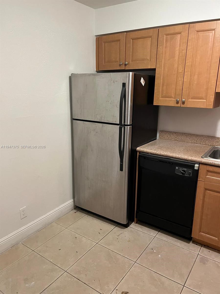 A kitchen features a stainless steel refrigerator, black dishwasher, and light wood cabinets — 5221 Geneva Way # 302, Doral FL 33166, DORAL, FL