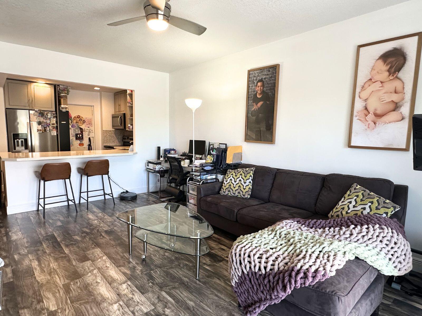 A living room with wood-look flooring, a dark sofa, glass coffee table, and open kitchen — 50 SW 3rd Avenue # 3020, Boca Raton FL 33432, BOCA RATON, FL