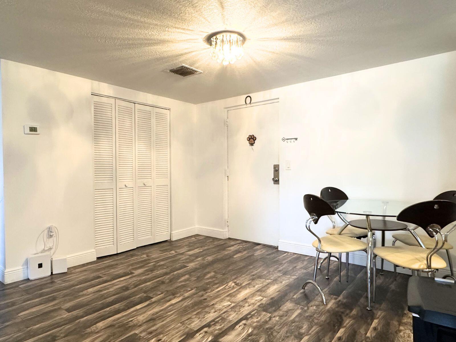A dining area features wood-look flooring, white walls, a glass table, and a crystal light fixture — 50 SW 3rd Avenue # 3020, Boca Raton FL 33432, BOCA RATON, FL