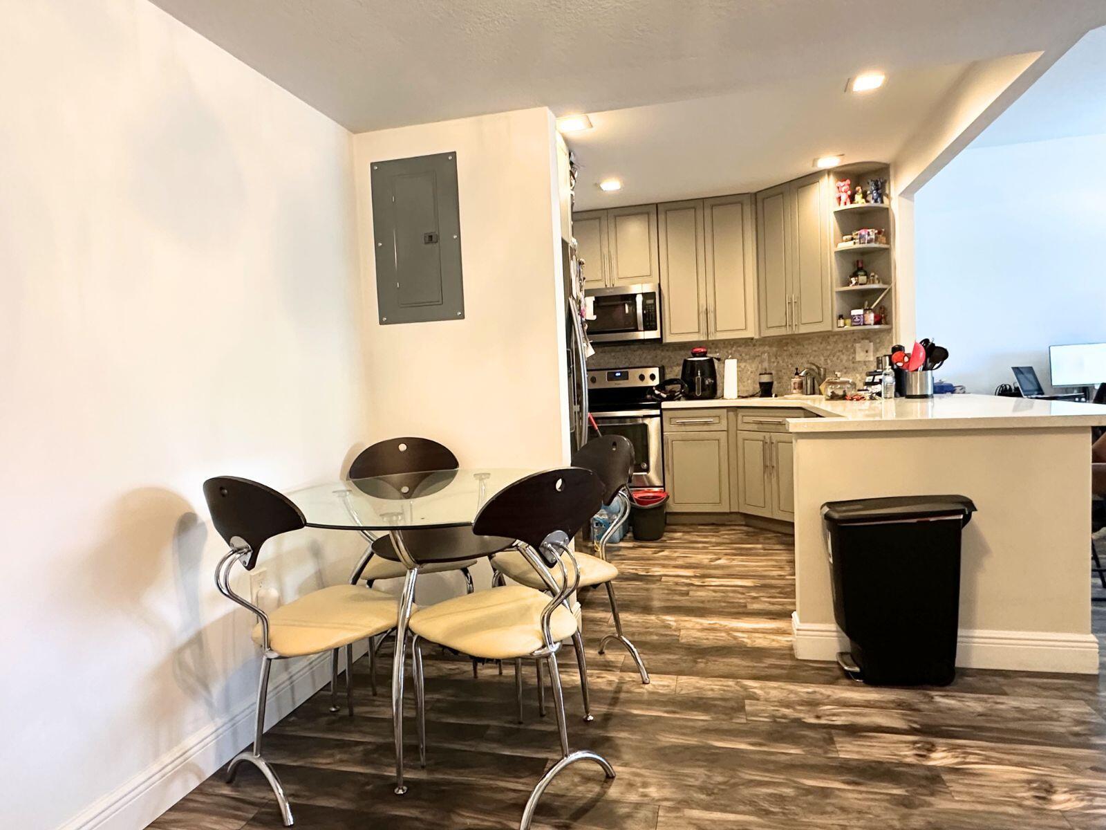 A kitchen with light-colored cabinets and a glass-topped dining table in the foreground — 50 SW 3rd Avenue # 3020, Boca Raton FL 33432, BOCA RATON, FL