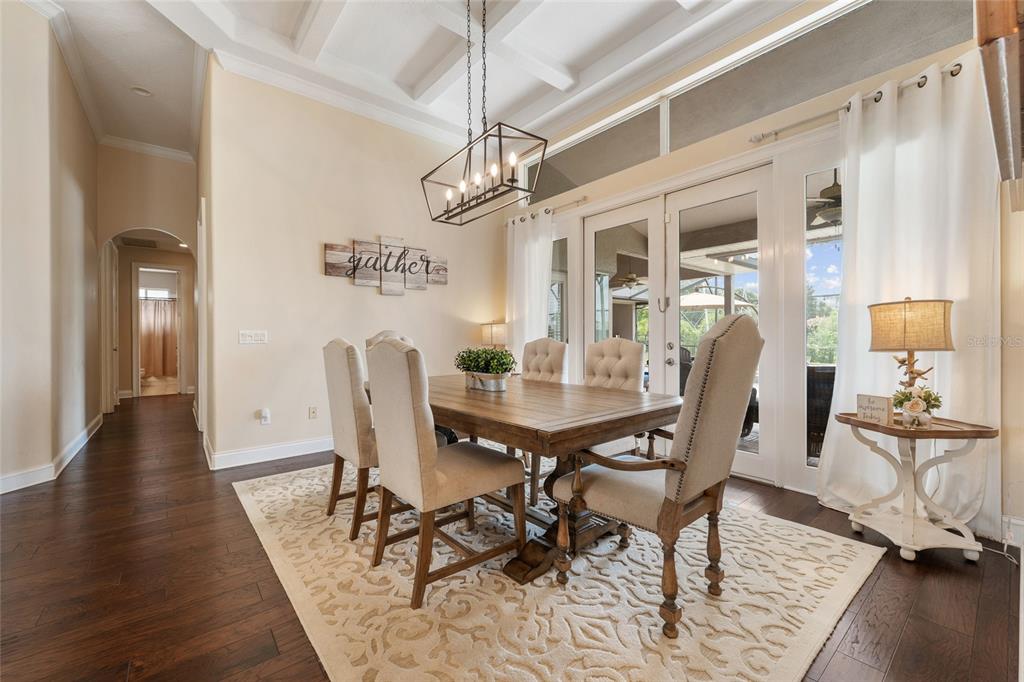 A dining room features a wooden table, upholstered chairs, a chandelier, and glass patio doors — 8612 OLDBRIDGE LANE, ORLANDO, FL