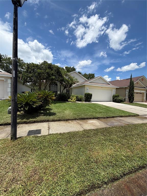 A single-story suburban house with a beige exterior, a two-car garage, and a manicured lawn — 5554 LIGUSTRUM LOOP, OVIEDO, FL