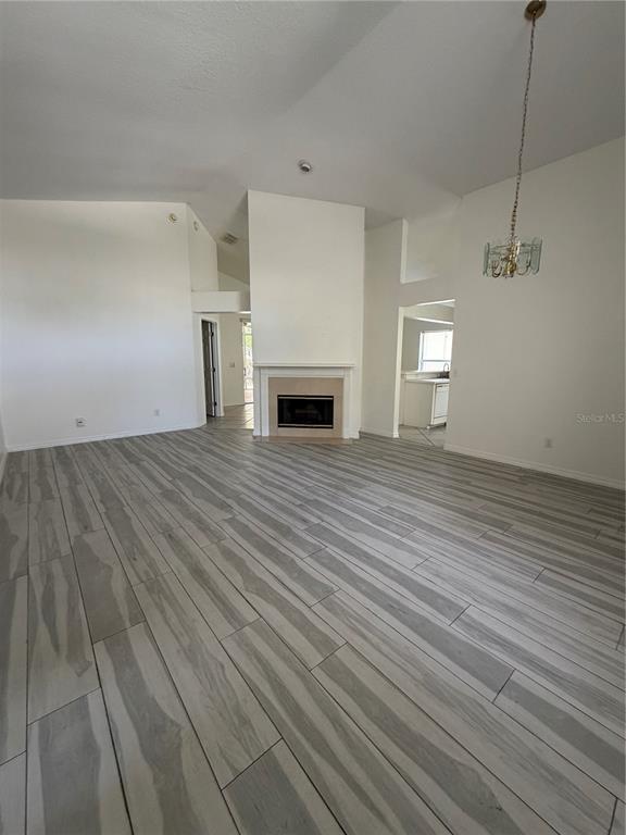 A living room features vaulted ceilings, light wood-look tile flooring, and a central fireplace — 5554 LIGUSTRUM LOOP, OVIEDO, FL