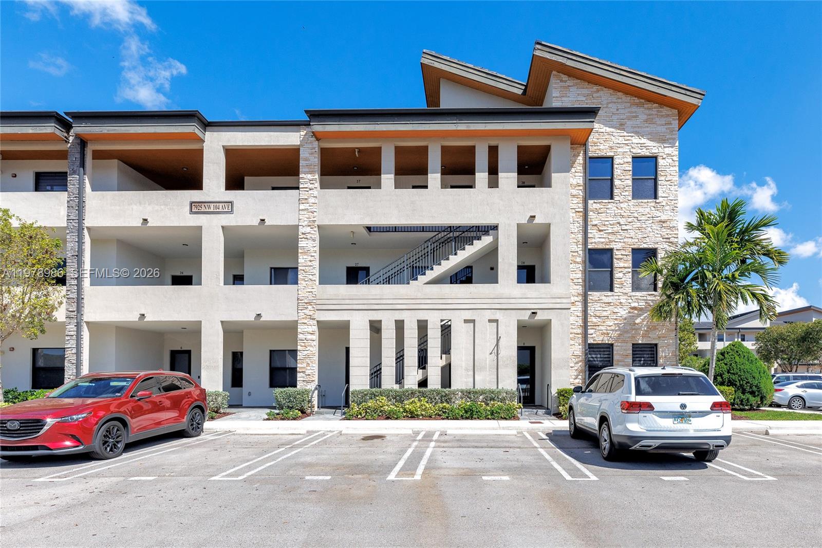A three-story apartment building features stone accents, a central staircase, and a parking lot — 7925 NW 104th Ave # 28, Doral FL 33178, DORAL, FL