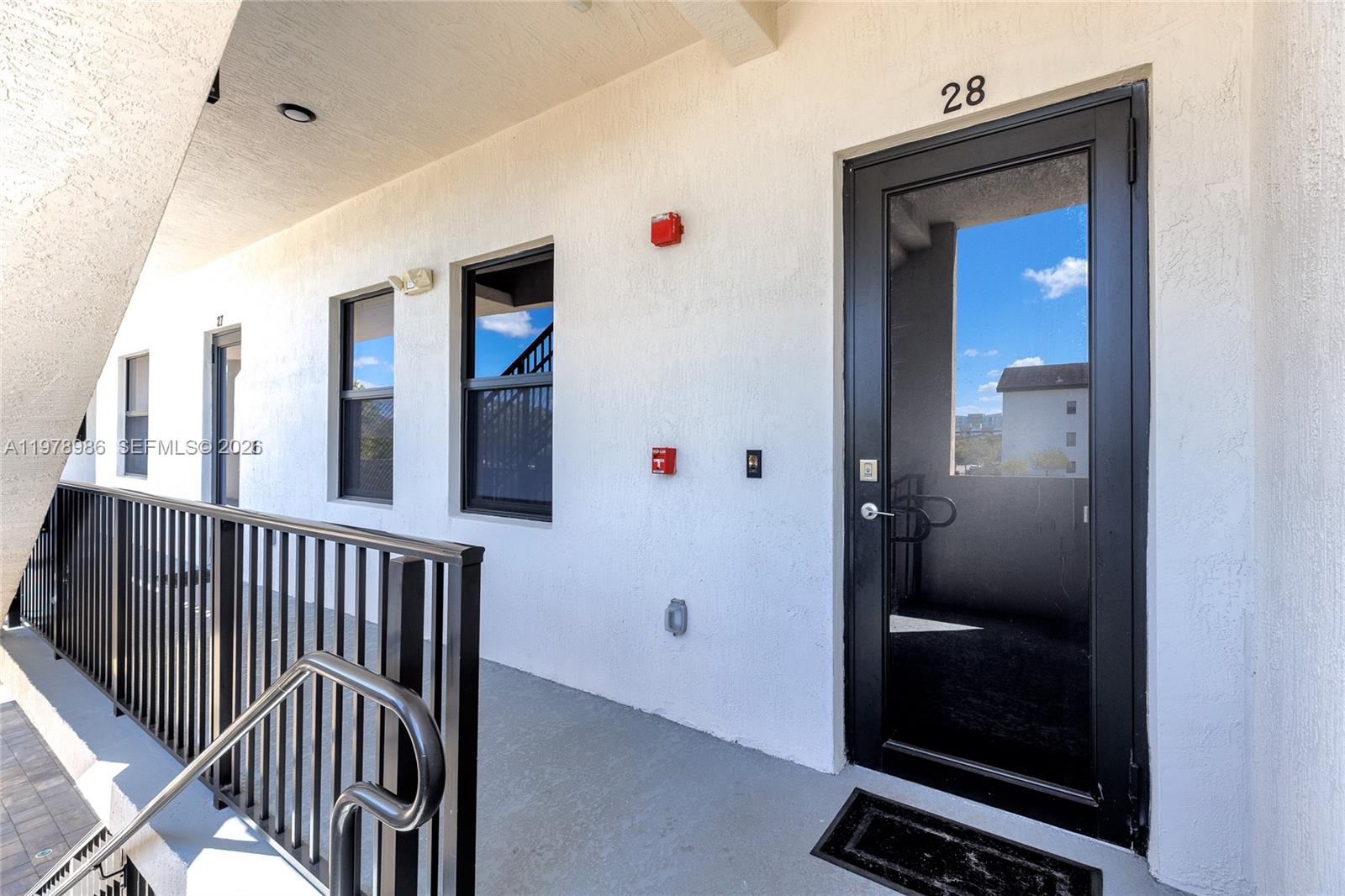 An exterior walkway features a black door labeled 28, windows, and a metal railing — 7925 NW 104th Ave # 28, Doral FL 33178, DORAL, FL