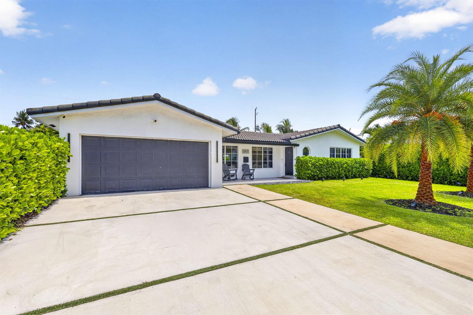 A white house with a dark garage door, a palm tree, and a concrete driveway — 2917 NE 35th Court, Lighthouse Point FL 33064, LIGHTHOUSE POINT, FL