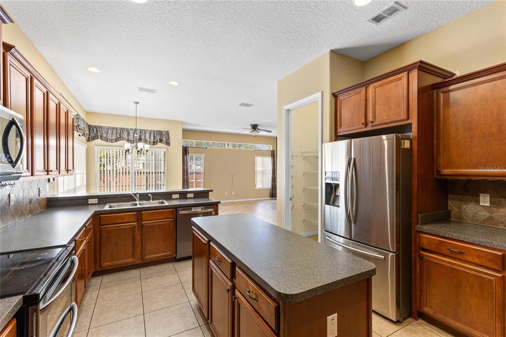 A kitchen with wood cabinets, stainless steel appliances, a central island, and tile flooring — 16407 BRISTOL LAKE CIRCLE, ORLANDO, FL