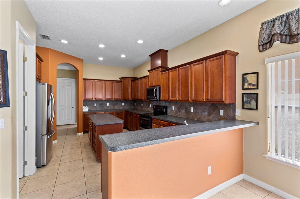 A kitchen features cherry wood cabinets, dark countertops, a center island, and a breakfast bar — 16407 BRISTOL LAKE CIRCLE, ORLANDO, FL