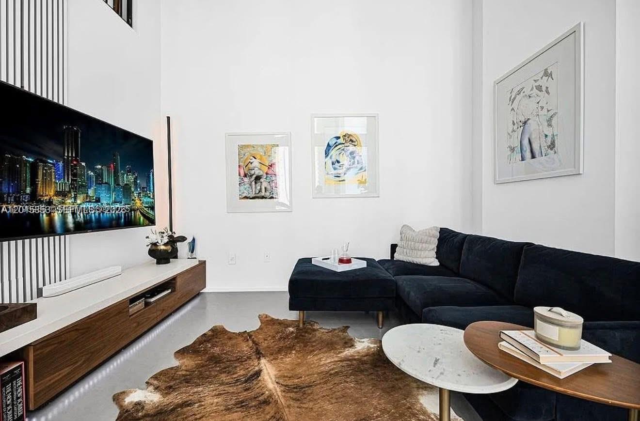 A living room features a dark sectional sofa, a cowhide rug, and a wall-mounted television — 300 S Biscayne Blvd # 1232, Miami FL 33131, MIAMI, FL