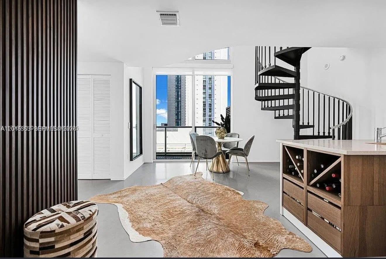 A modern living and dining area features a spiral staircase, wood-paneled wall, and balcony access — 300 S Biscayne Blvd # 1232, Miami FL 33131, MIAMI, FL