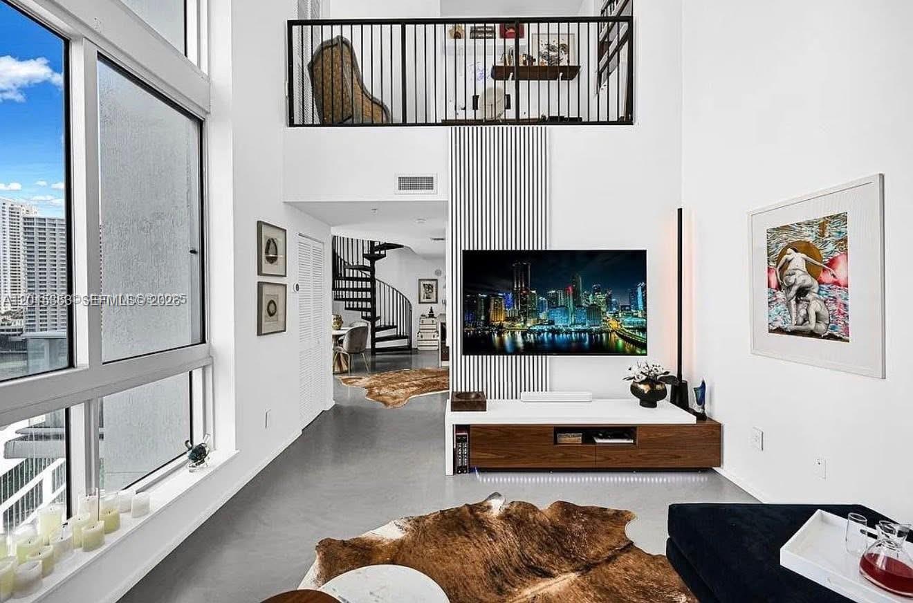 A modern living room features a two-story ceiling, a spiral staircase, and a loft balcony — 300 S Biscayne Blvd # 1232, Miami FL 33131, MIAMI, FL
