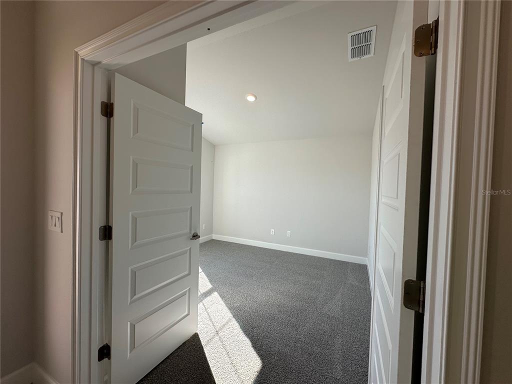 A view through double doors into an empty room with gray carpet and white walls — 12543 NE 48TH TERRACE, OXFORD, FL