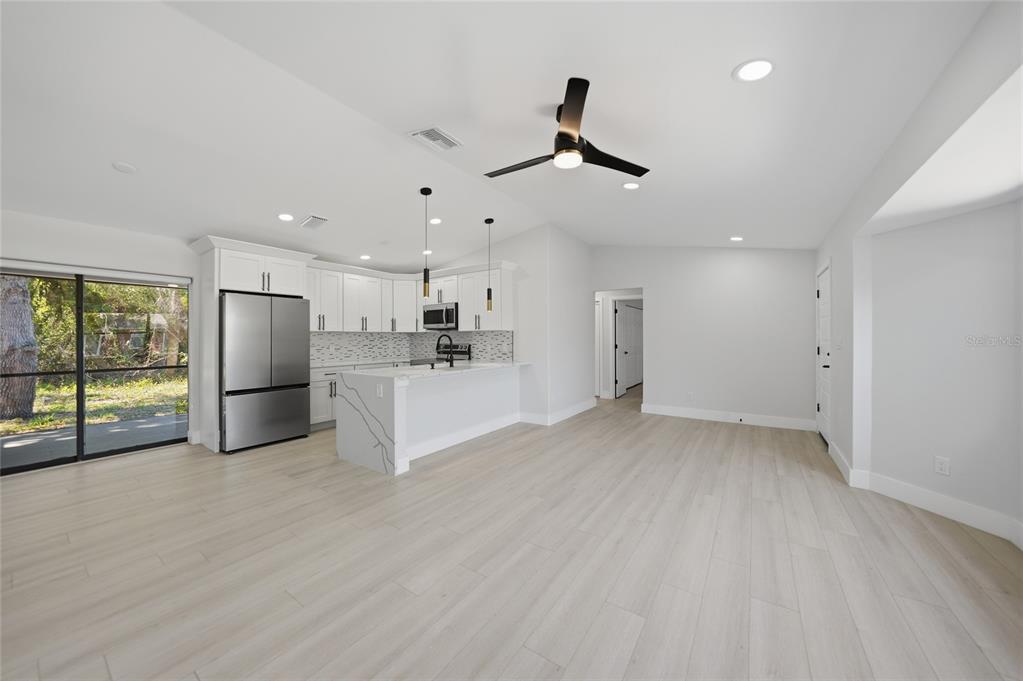 A modern kitchen with white cabinets and a marble-patterned island opens into a living area — 5009 JODY AVENUE, NORTH PORT, FL