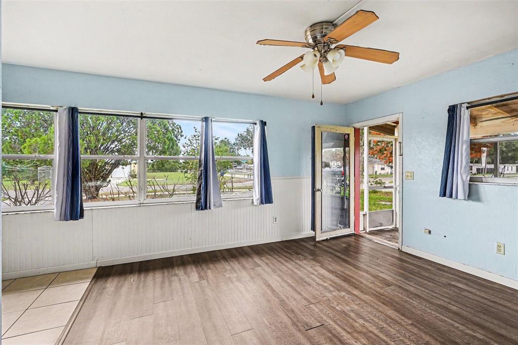 A living room with light blue walls, wood-look flooring, a ceiling fan, and large windows — 520 S ORANGE AVENUE, FORT MEADE, FL