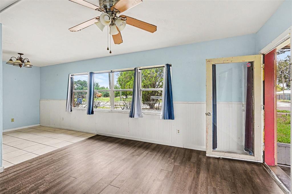 A living room with light blue walls, white wainscoting, wood-look flooring, and a ceiling fan — 520 S ORANGE AVENUE, FORT MEADE, FL