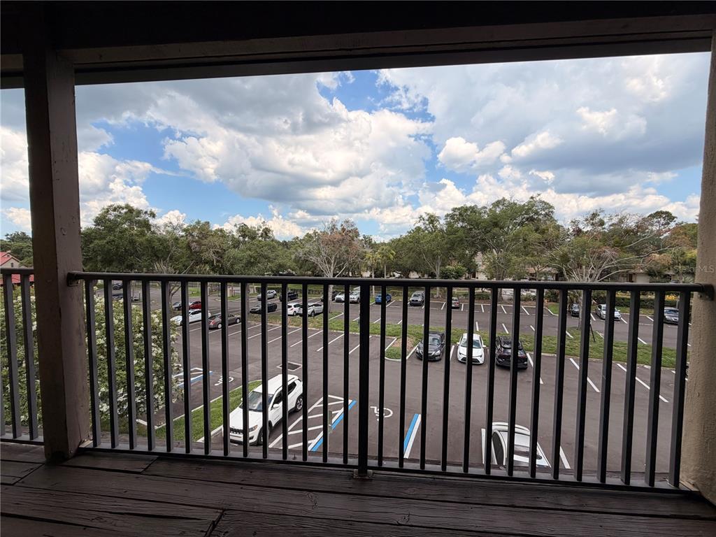 A view from a covered balcony overlooking a parking lot with trees and a cloudy sky — 232 AFTON SQUARE UNIT 309, ALTAMONTE SPRINGS, FL