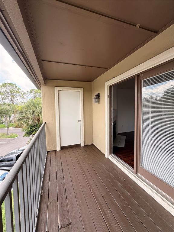 A covered balcony features dark wood decking, a white storage door, and a sliding glass door — 232 AFTON SQUARE UNIT 309, ALTAMONTE SPRINGS, FL