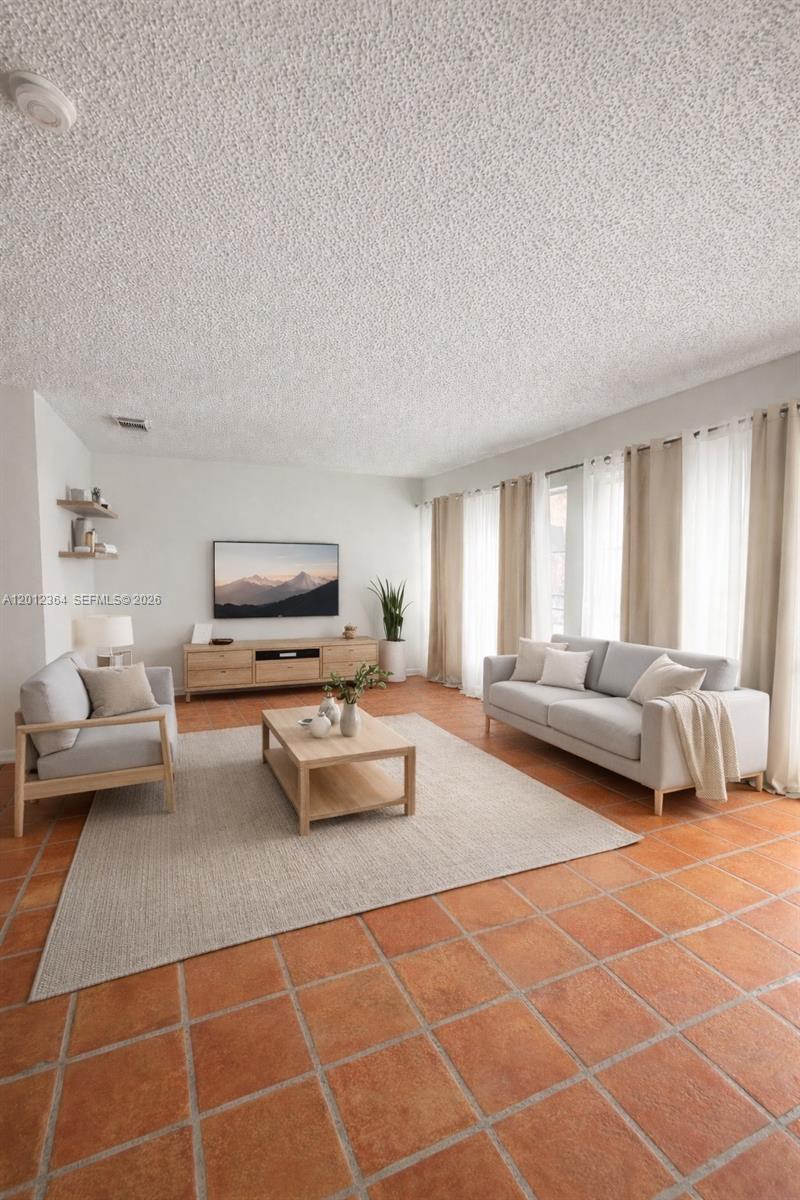 An empty room features terracotta tile flooring, white walls, a textured ceiling, and floor-to-ceiling curtains — 1045 NW 126th Pl, Miami FL 33182, MIAMI, FL