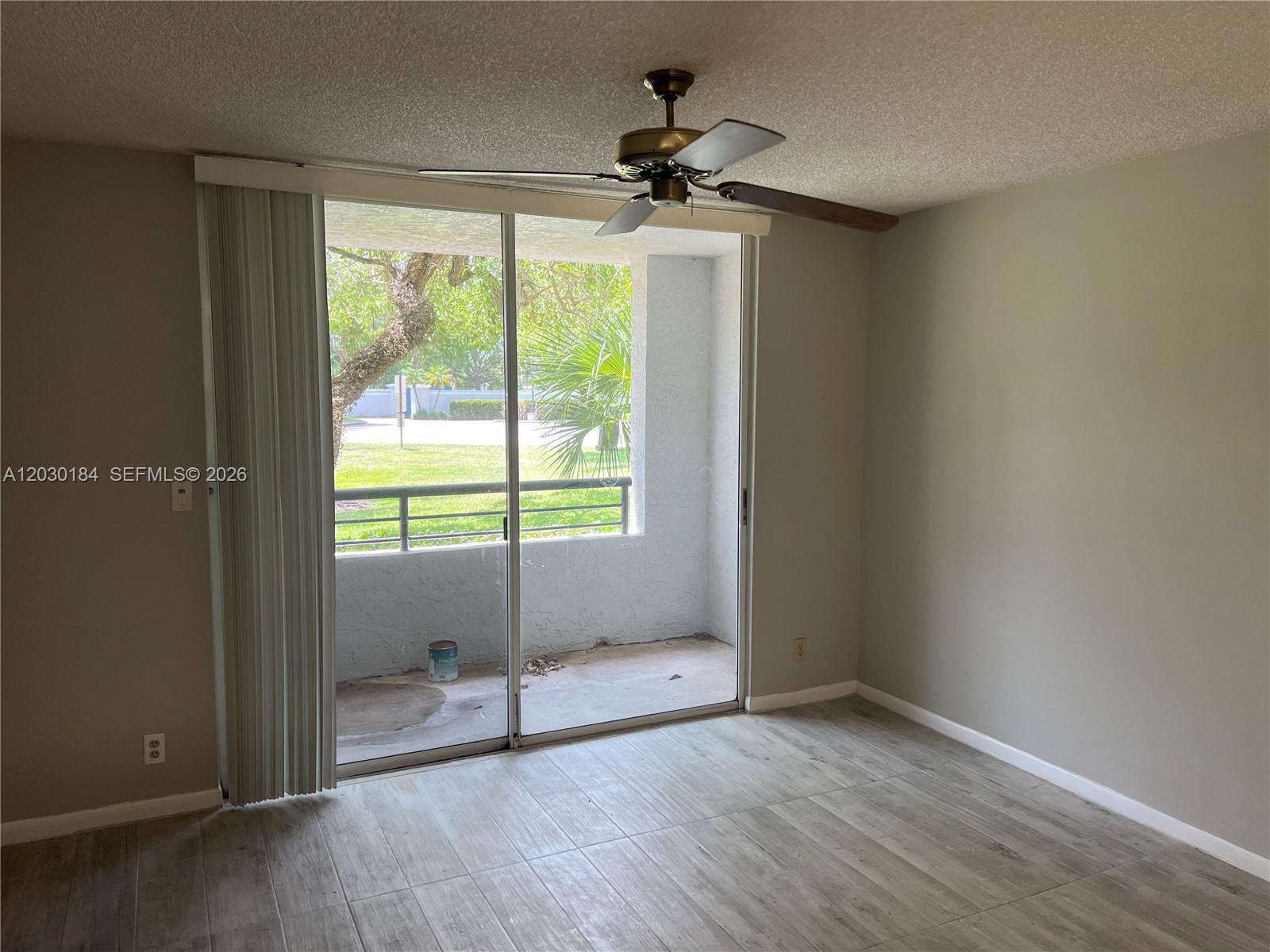 A room with light wood-look tile flooring, a ceiling fan, and sliding doors to a balcony — 951 Lyons Rd # 6104, Coconut Creek FL 33063, COCONUT CREEK, FL