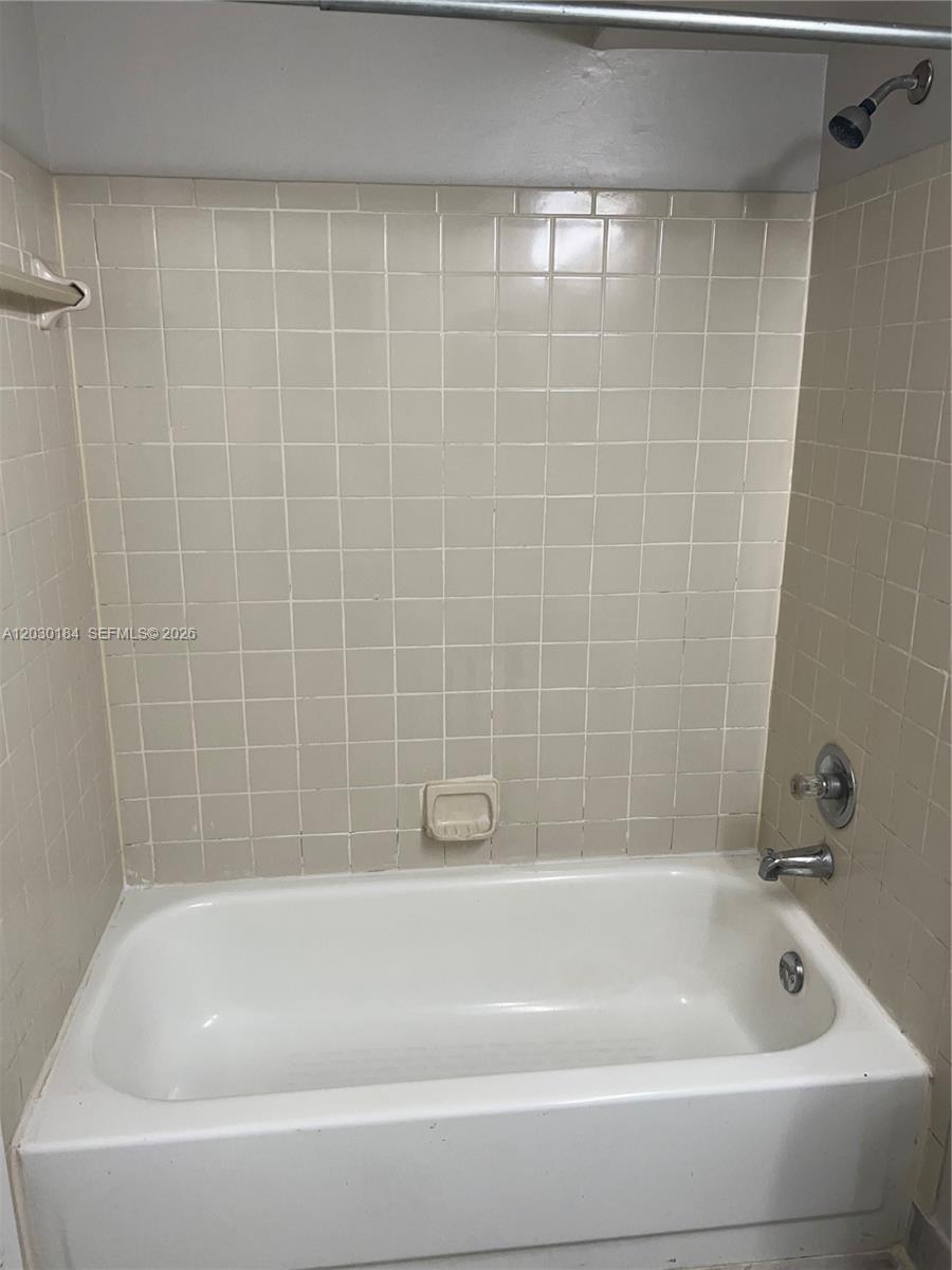 A white bathtub is surrounded by beige square wall tiles and a shower head — 951 Lyons Rd # 6104, Coconut Creek FL 33063, COCONUT CREEK, FL