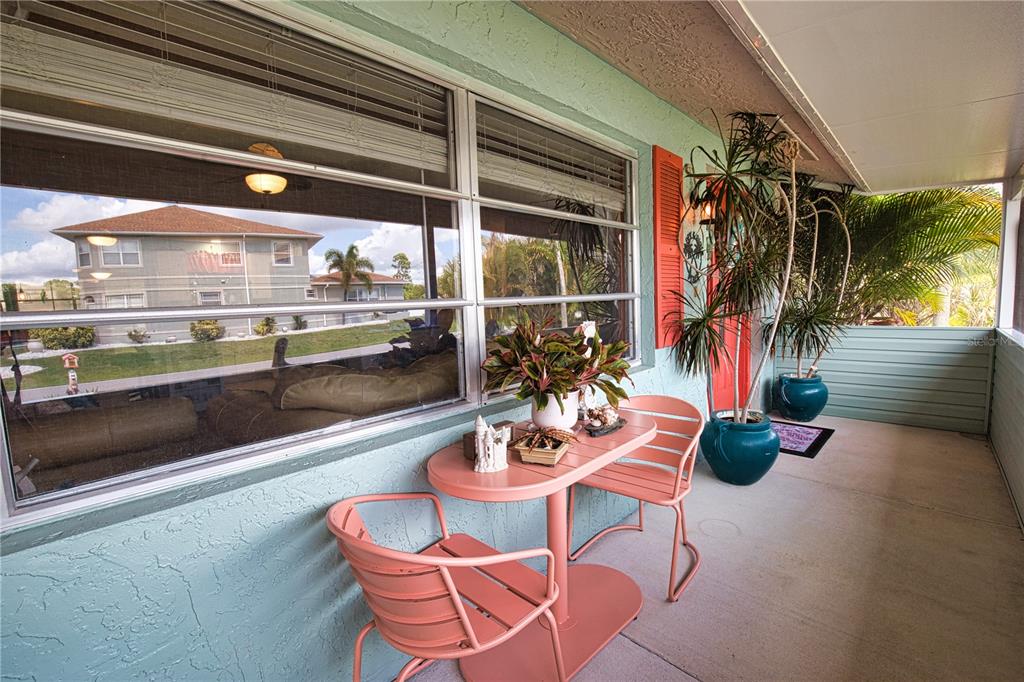 A covered patio features a small pink metal bistro set and potted plants — 457 W TARPON BOULEVARD NW, PORT CHARLOTTE, FL