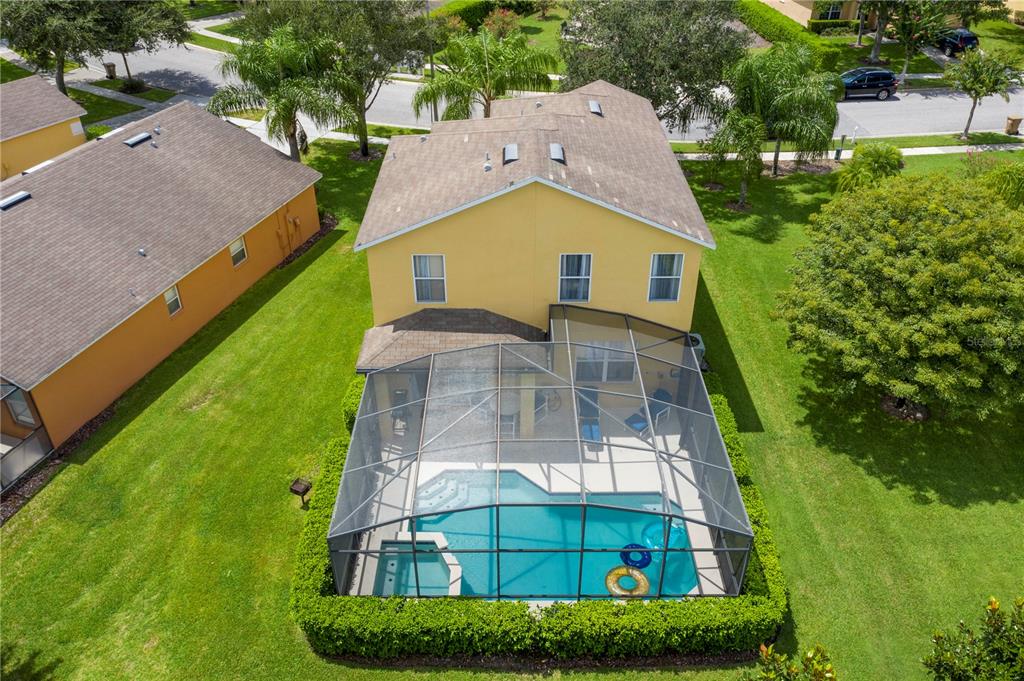 An aerial view of a two-story yellow house with a screened-in pool and patio — 17614 WOODCREST WAY, CLERMONT, FL