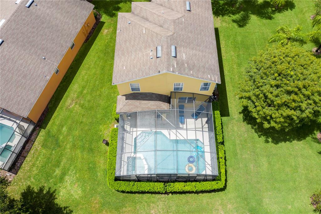 An aerial view shows a two-story house with a screened-in pool and backyard landscaping — 17614 WOODCREST WAY, CLERMONT, FL
