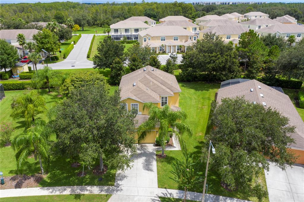 An aerial view shows a yellow two-story house with a driveway and surrounding trees — 17614 WOODCREST WAY, CLERMONT, FL