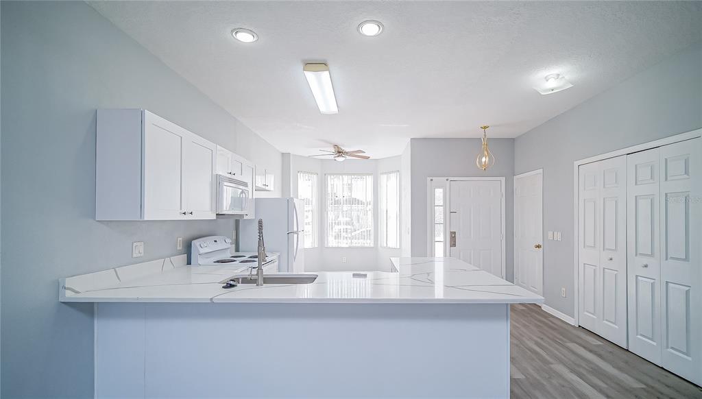 A kitchen with white cabinets, a quartz countertop island, and light-colored flooring — 1288 S BEACH CIRCLE, KISSIMMEE, FL