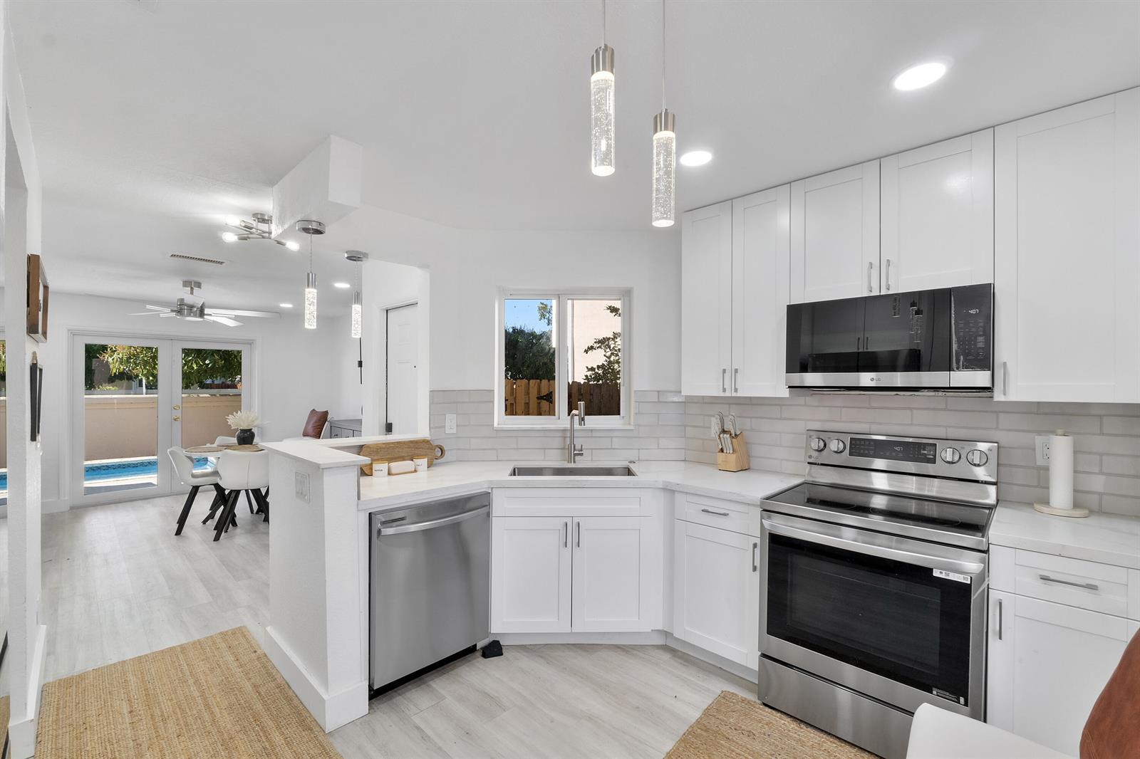 A modern kitchen with white cabinets, stainless steel appliances, and a view of a pool — 6363 Seagrape Circle, Margate FL 33063, MARGATE, FL