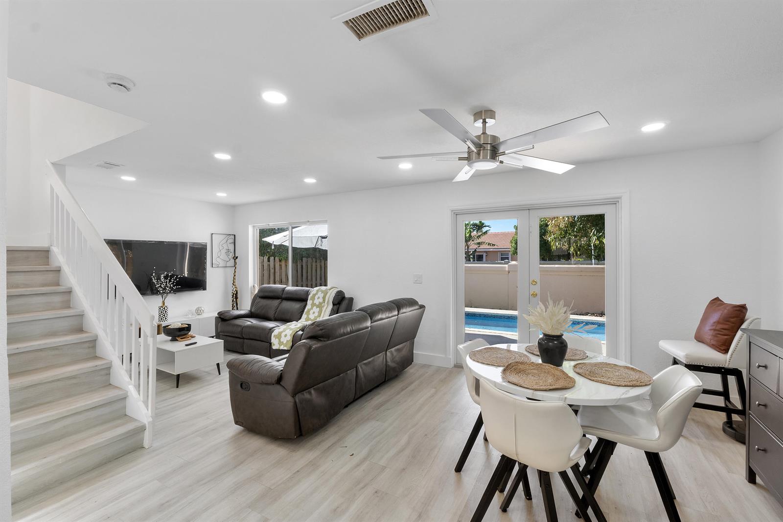 A living and dining area features light wood flooring, a staircase, and a backyard pool — 6363 Seagrape Circle, Margate FL 33063, MARGATE, FL