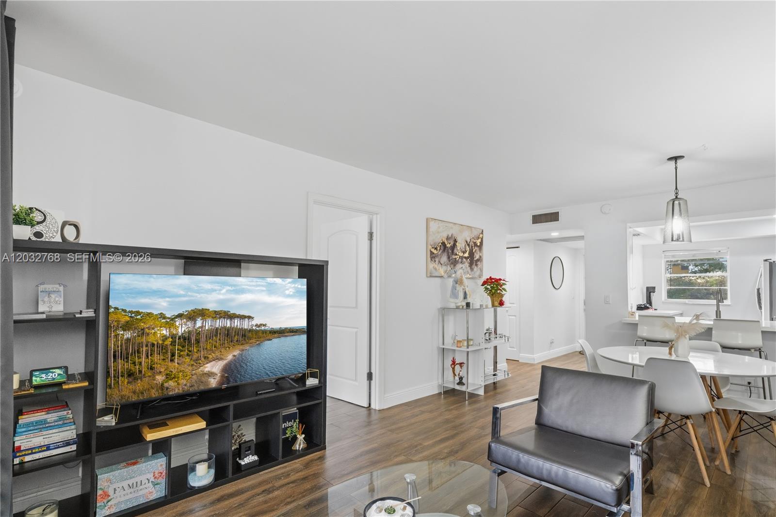 A living room features dark wood flooring, a black media console, and an adjacent dining area — 9340 Lagoon Pl # 304, Davie FL 33324, DAVIE, FL
