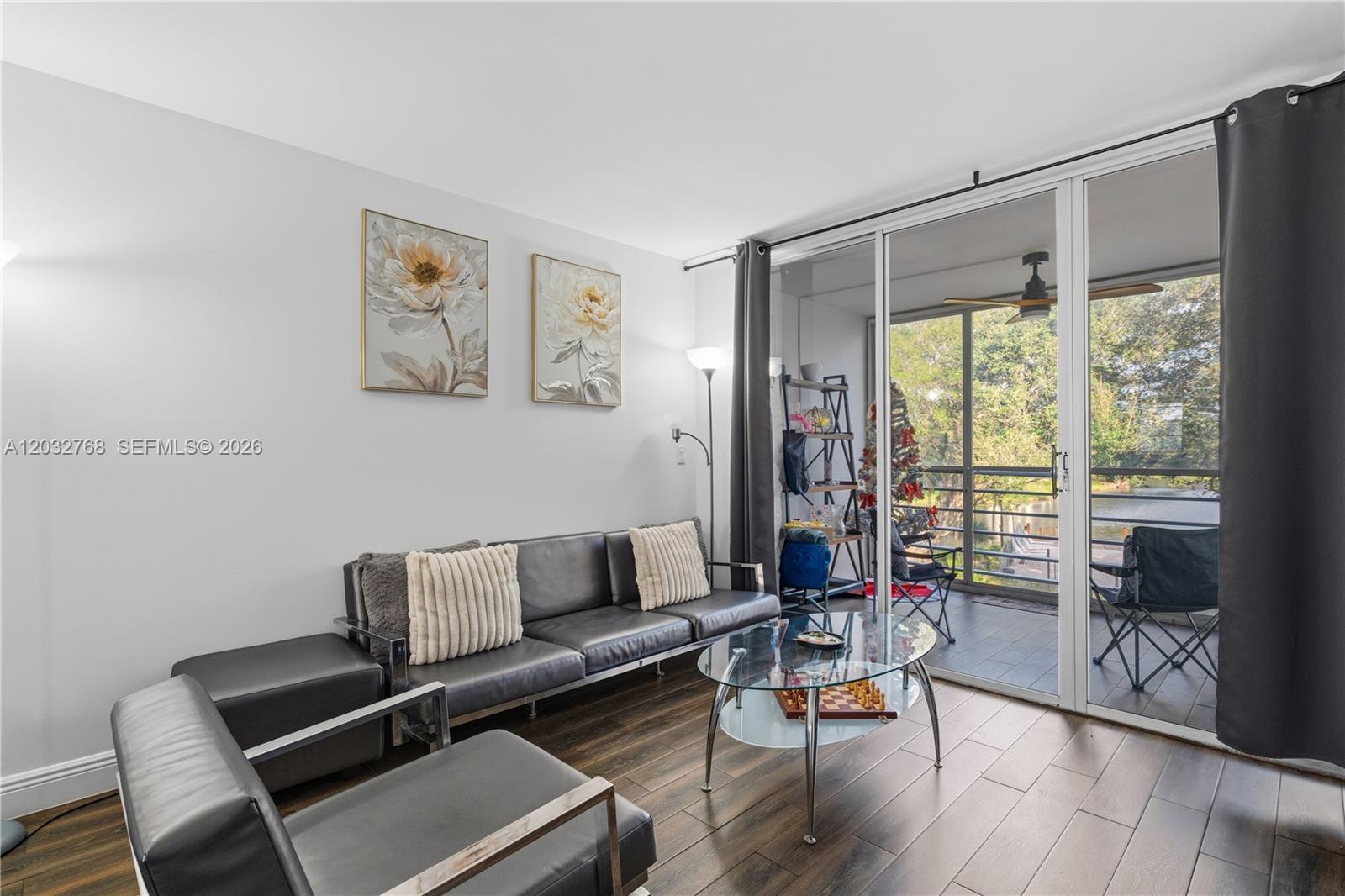 A living room features dark leather furniture, a glass coffee table, and a sliding door — 9340 Lagoon Pl # 304, Davie FL 33324, DAVIE, FL